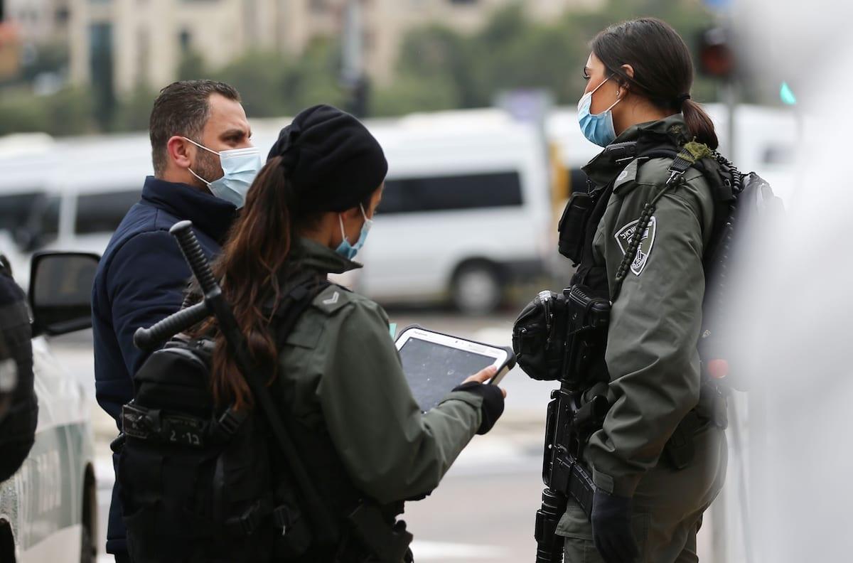 Jerusalem police stop a Palestinian passerby to conduct an ID card search using an iPad