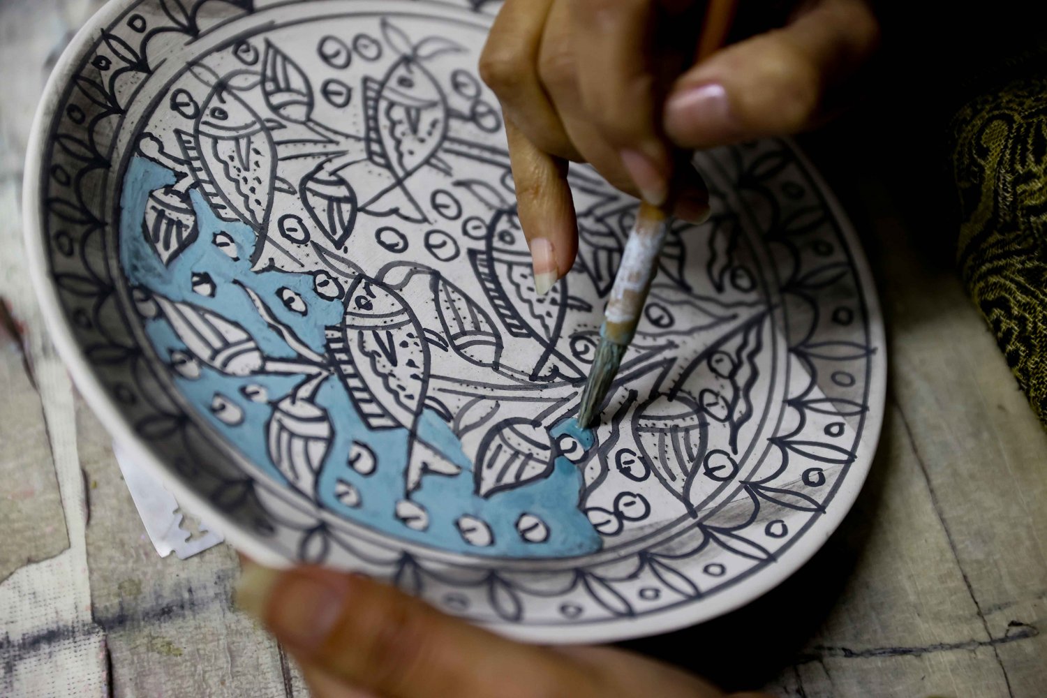 A ceramic artist handpaints bright colors on an Armenian pottery plate at the Balian workshop in Jerusalem