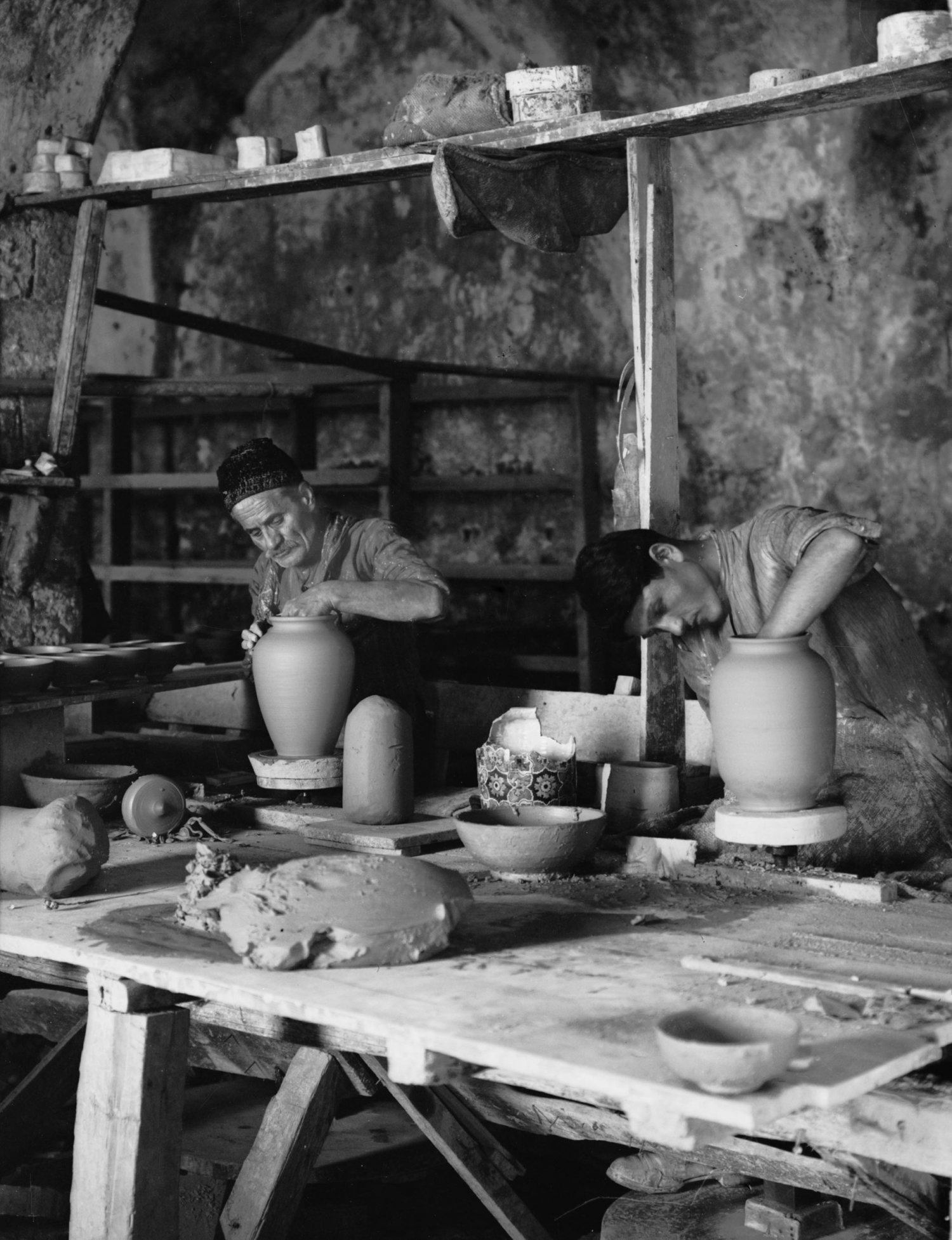 Male potters shape earthenware jars on the wheels at the Dome of the Rock Tiles workshop, Via Dolorosa, Jerusalem, 1920s